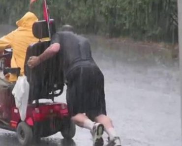 Kind Man Pushes An Electric Wheelchair Uphill During A Thunder Storm